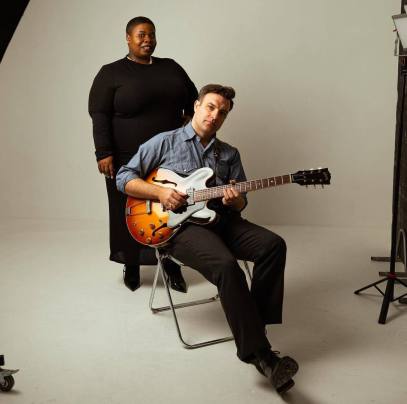 PM Warson sitting with guitar in front of Carmy Love