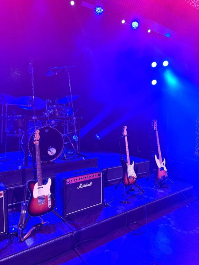 Three guitars and a drum kit on stage for the Rave On tour